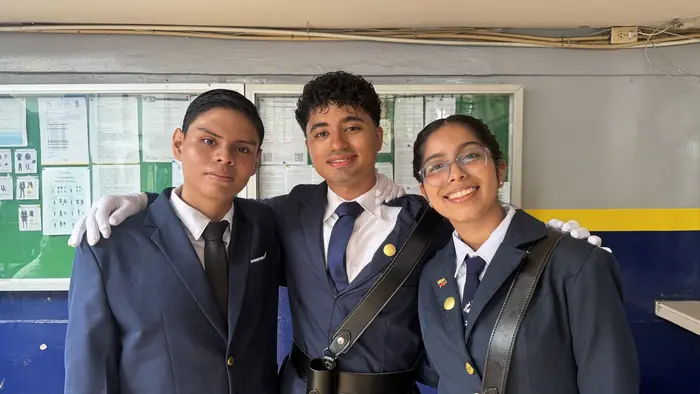 Tres escoltas 2026-2027 del colegio Juan XXIII sonriendo con su uniforme de gala