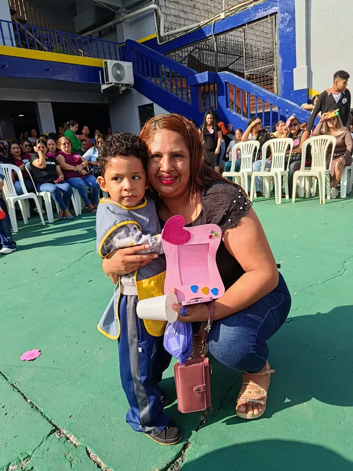Niño de Inicial del colegio Juan XXIII abrazando a su mamá con el regalo que preparó