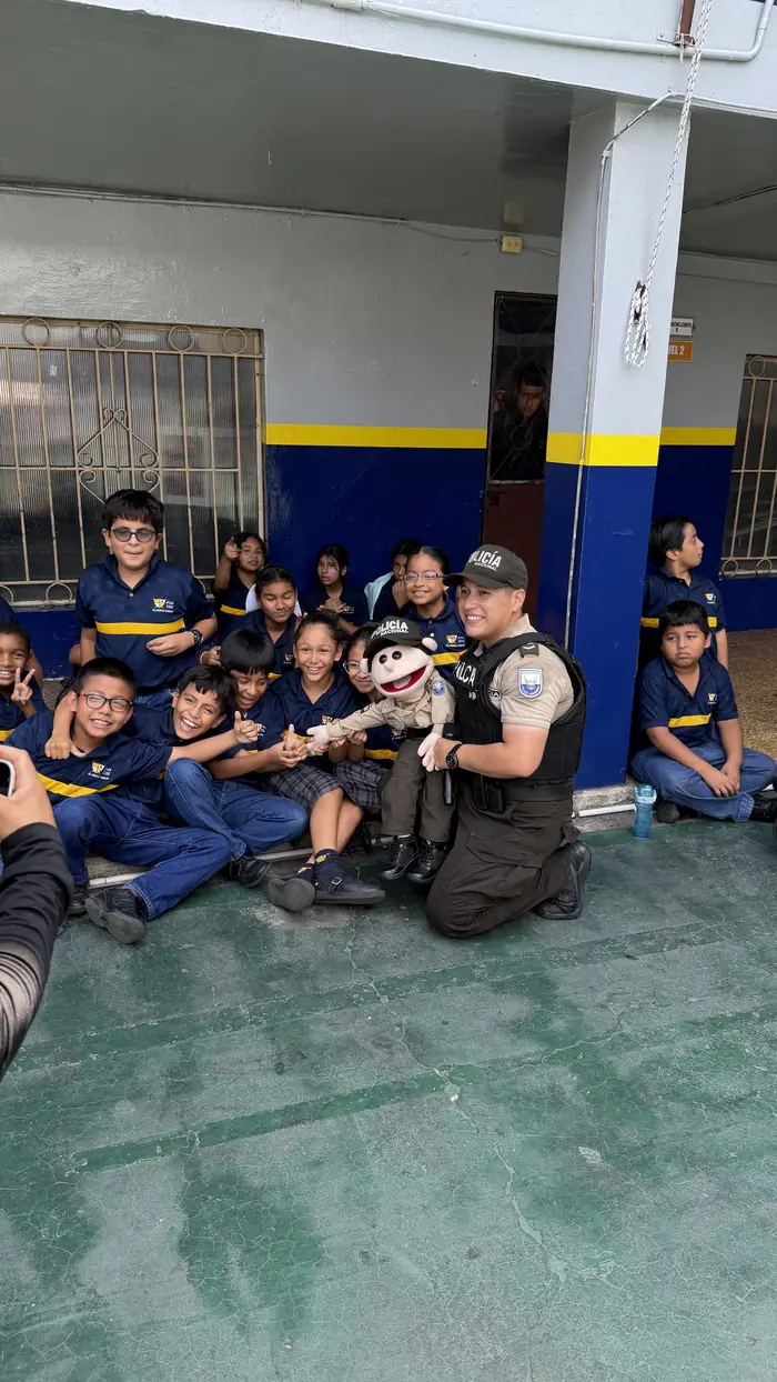 Estudiantes del colegio Juan XXIII sentados en el patio junto a Paquito Policía